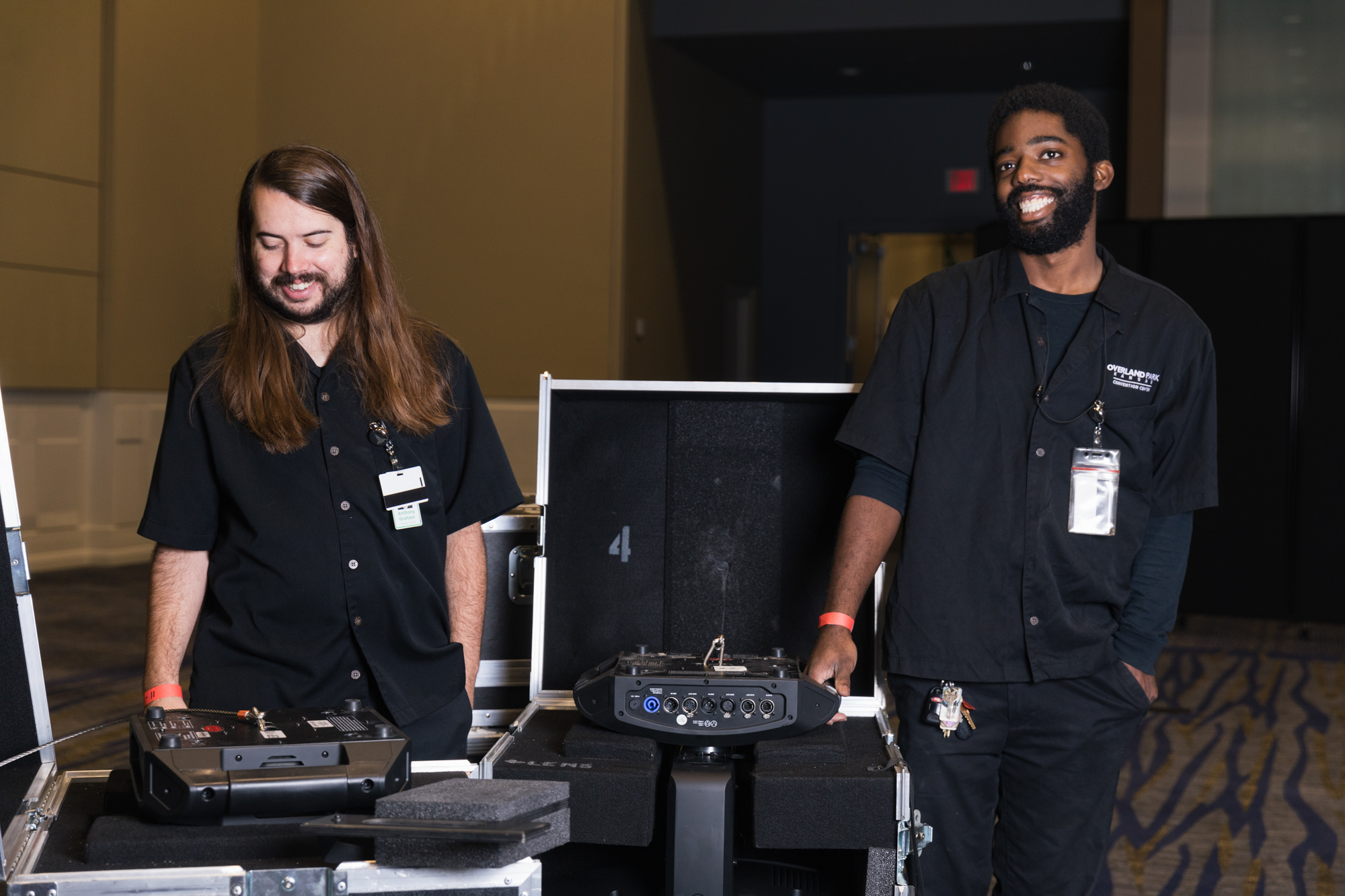 A pair of A/V experts in black uniforms prepare a presentation, helping us stay ahead of healthcare industry event trends.