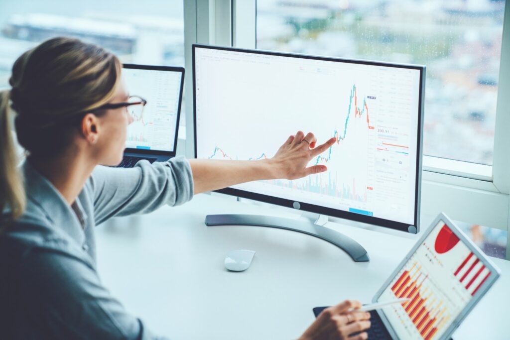 A woman points at a monitor and plans out a business strategy after reading ur Guest Post: Marketing